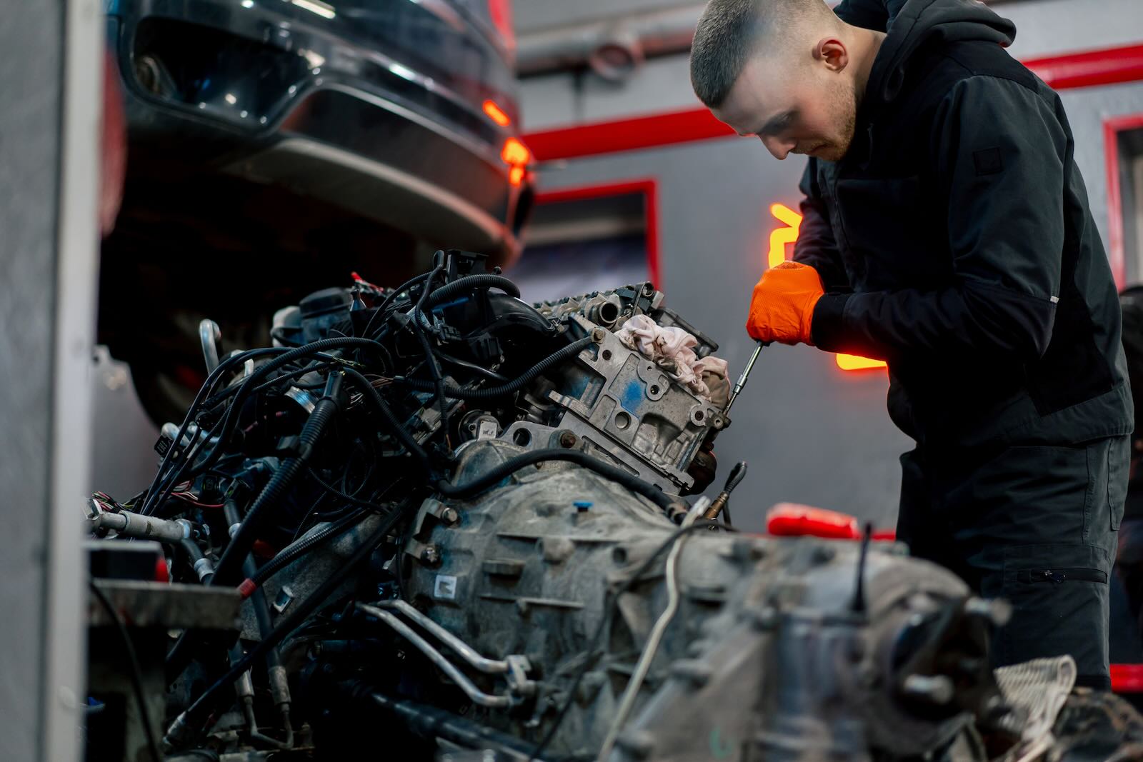 Young man removes an engine from a stolen muscle car in a Miami chop shop