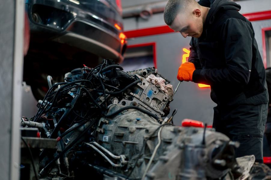 Young man removes an engine from a stolen muscle car in a Miami chop shop