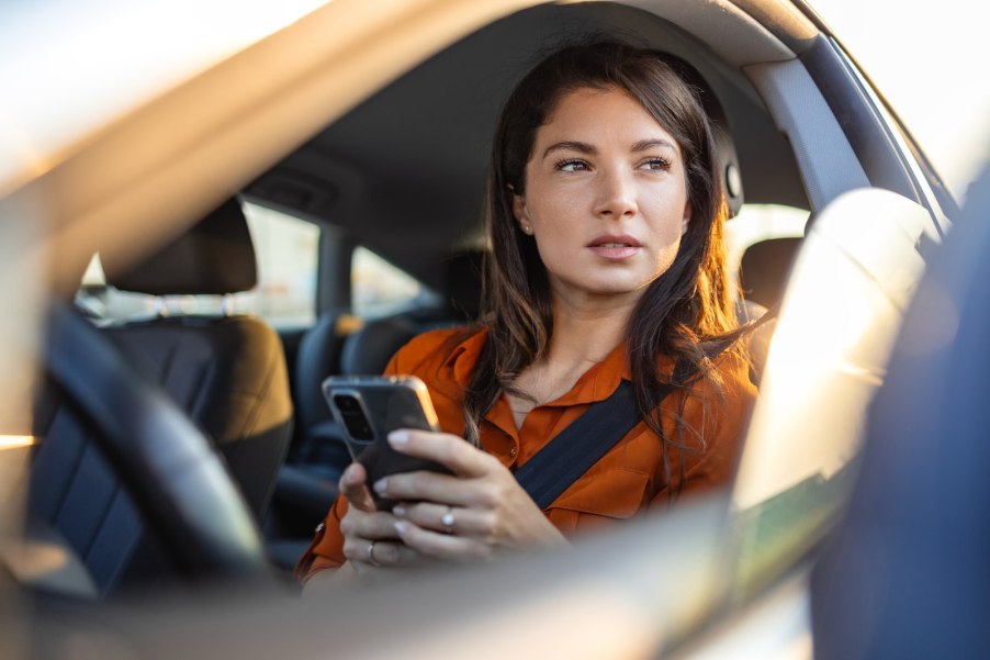 Woman driver holding a cellphone she was using for navigation.