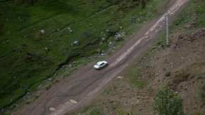 White Peugeot Pars drives along a dirt road in rural Iran.