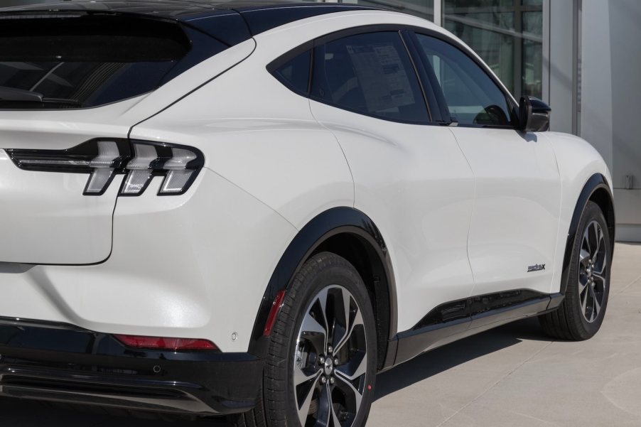 Rear view of a white Ford Mustang Mach-E crossover at a dealership.