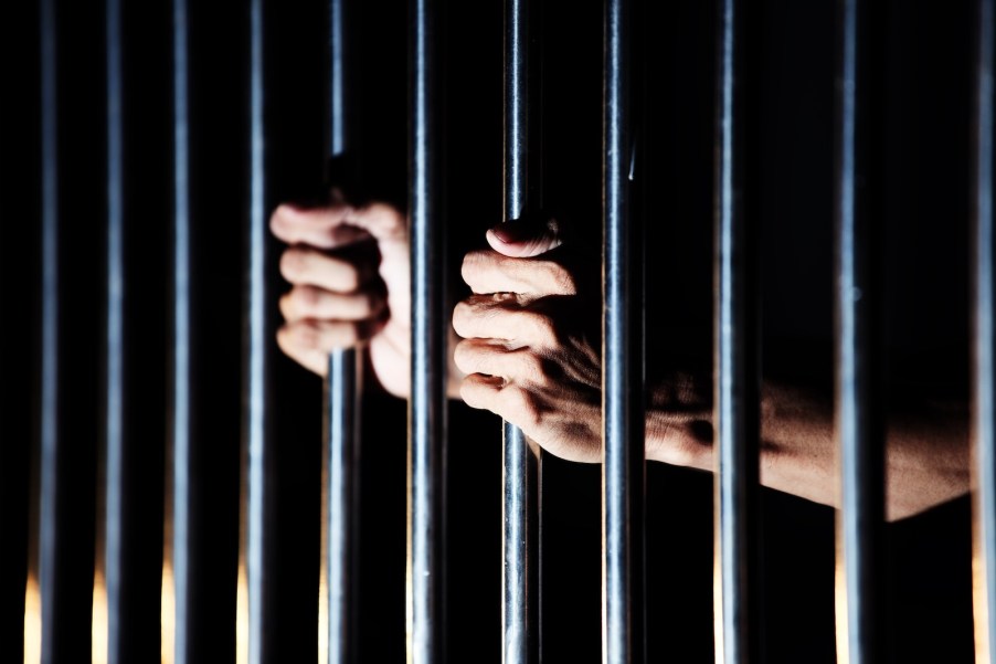 Prisoner's hands on a florida jail cell bars for a first-time speeding offense