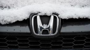 The grille badge on a Honda Accord, covered in a dusting of snow.