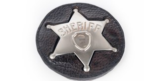 Silver Sheriff's badge on a black leather background.