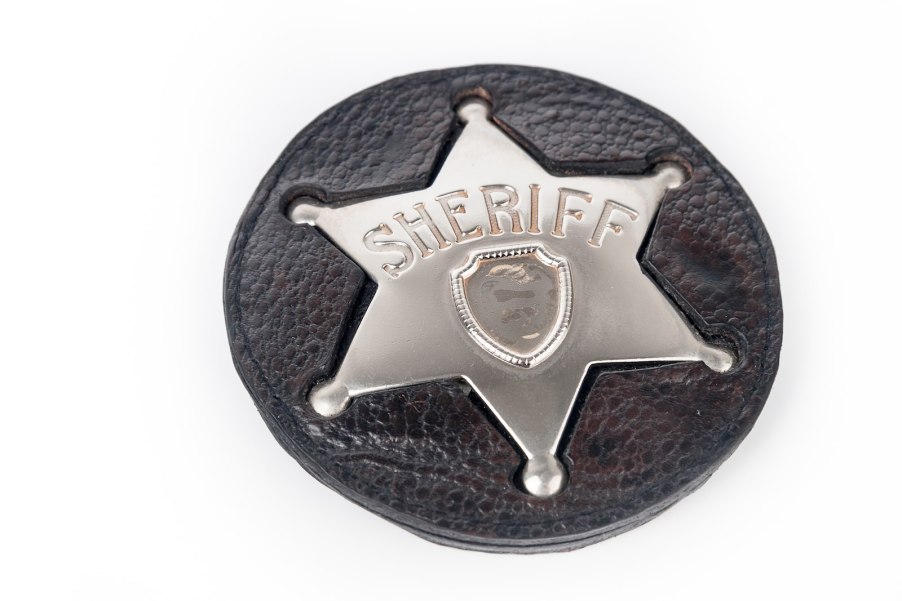 Silver Sheriff's badge on a black leather background.