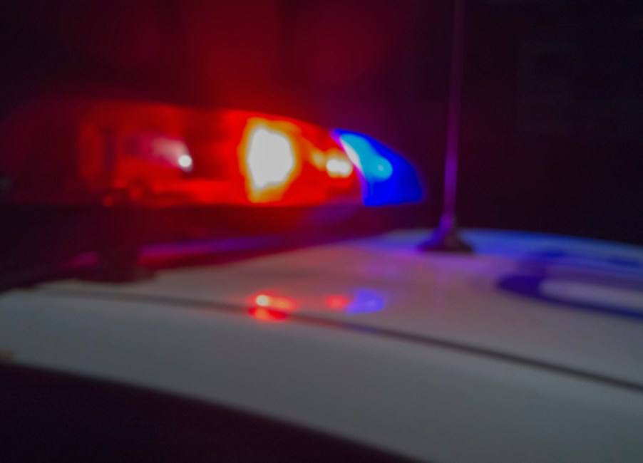 Police cruiser's red and blue lights during a nighttime chase after a dealership car theft.