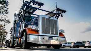 Semi truck parked in a lot with a car hauler trailer behind it