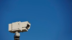 White speed camera in front of a blue sky.