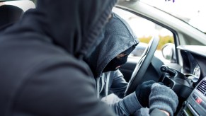 Two car thieves fumble with the ignition of a luxury sports car.