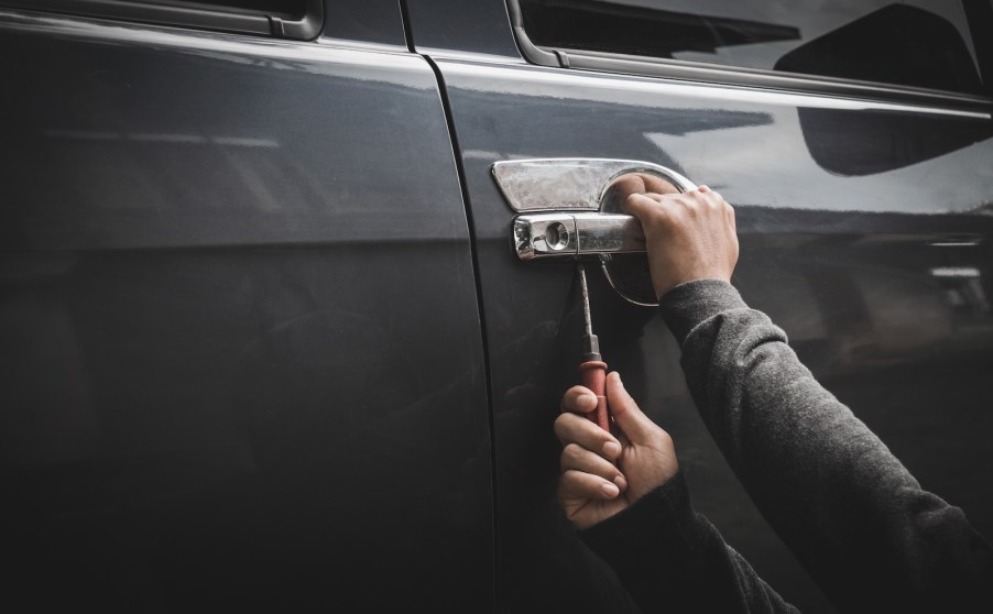 Hands of a thief holding tools to steal a Ford F-150 pickup truck
