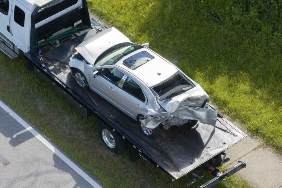 A silver vehicle on a tow truck bed after a car crash