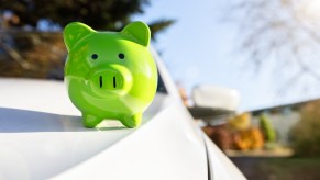 A green porcelain piggy bank sitting on a white car's hood