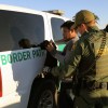A Border Patrol agent by an SUV stopping a heavy-duty truck
