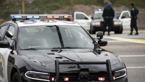 LAPD vehicles, one in close foreground and another in background with open doors and officers standing outside