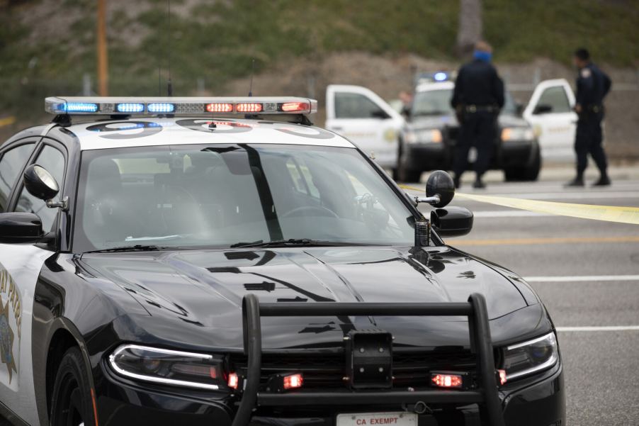 LAPD vehicles, one in close foreground and another in background with open doors and officers standing outside