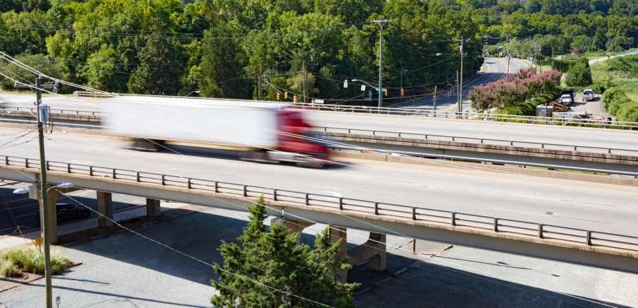A semi-truck speeds across a highway overpass