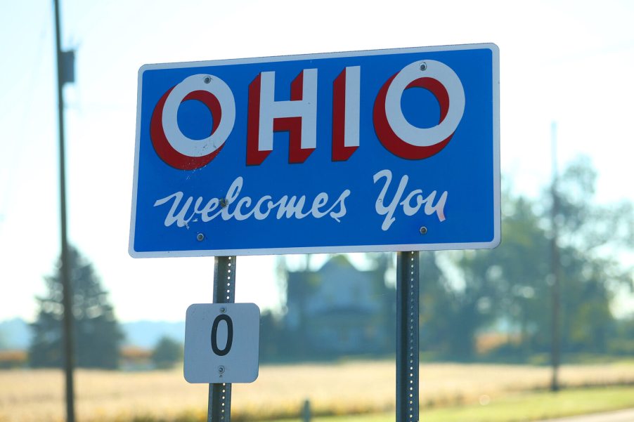 A blue, white, and red road sign reading "Ohio Welcome You"