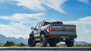 A 2012 Ford F-150 Raptor parked outside in lower left rear angle view