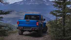 A blue 2025 Jeep Gladiator pickup parked facing a scenic overlook