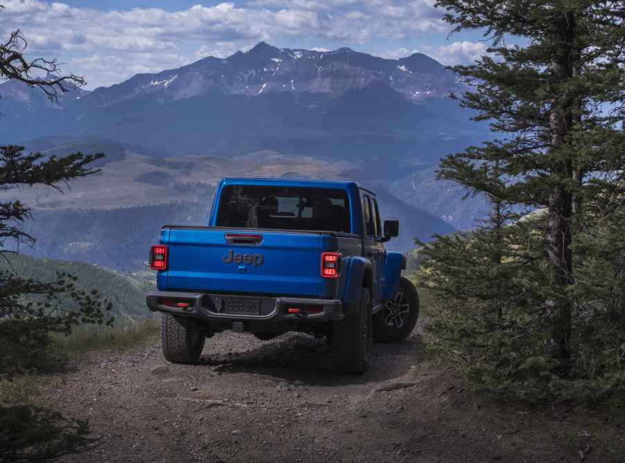 A blue 2025 Jeep Gladiator pickup parked facing a scenic overlook
