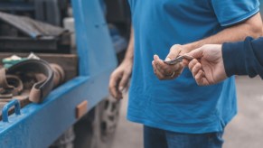 Car owner hands a wad of money to a tow truck driver for storage fees.