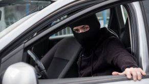Thief nabs luxury vehicle in dealership car heist, wearing a mask