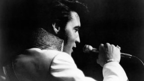 Singer Elvis Presley on stage in a black and white photo.