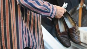 Man holds his leather loafer shoes as he walks through LAX airport security.