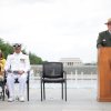 National Park Service speakers stands behind a podium next to military veterans to honor WWII