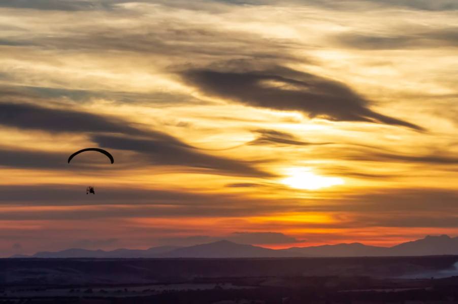 A powered paraglider at sunset.