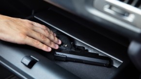 Thief takes a gun out of a car glovebox during a handgun theft.