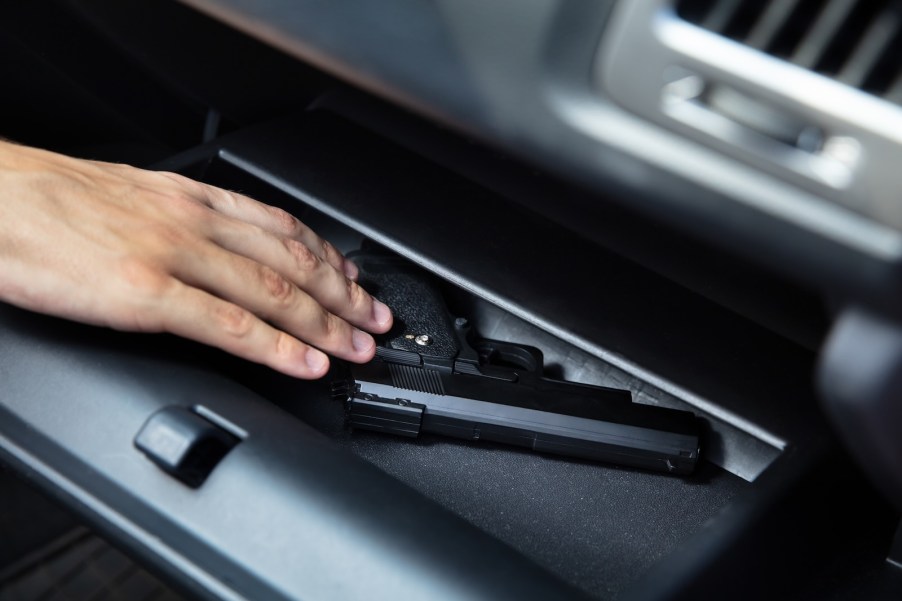 Thief takes a gun out of a car glovebox during a handgun theft.