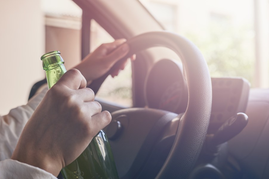A man holding a beer while driving