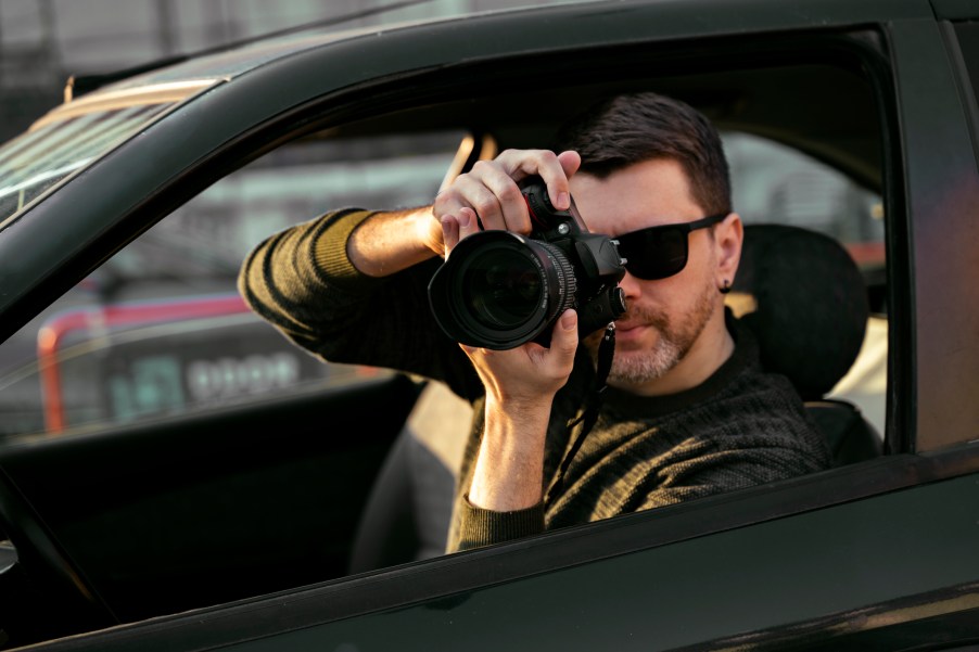 A detective in a car with a camera