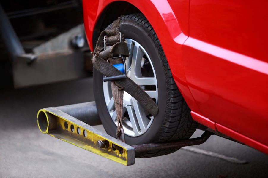 A red car getting a tow in very close view of a wheel