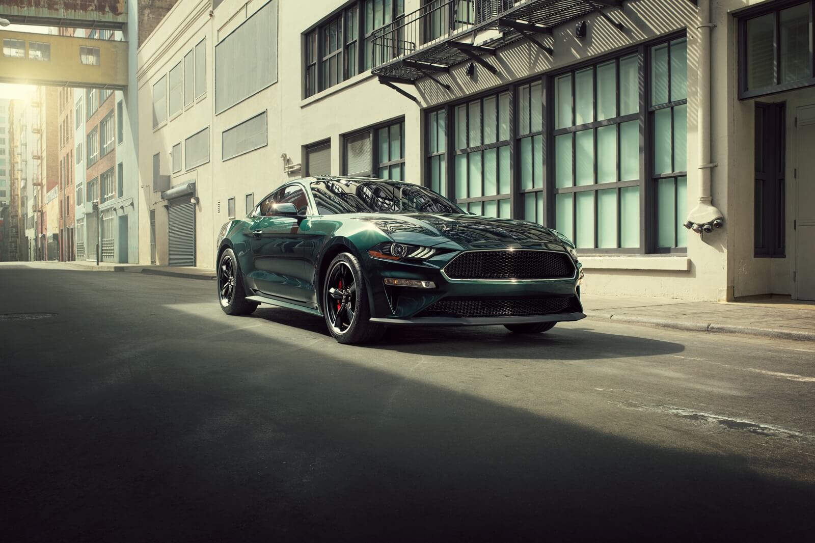 A Dark Highland Green Ford Mustang Bullitt on city streets.