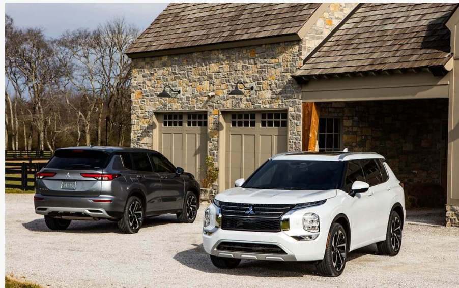 A set of 2022 Mitsubishi Outlander SUVs, which the brand just recalled, parked near a stone building.