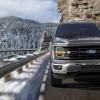 A 2025 Ford F-150 cruises around a mountain pass.