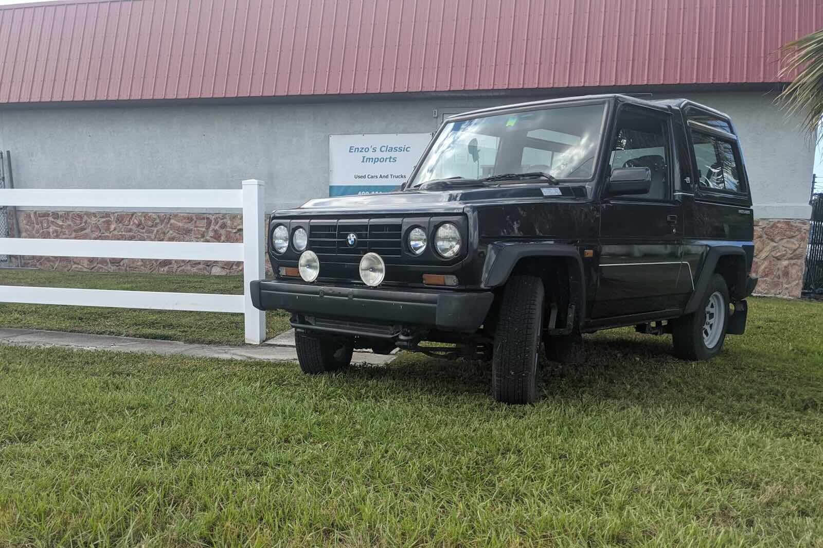 The front of a Bertone Freeclimber SUV with its BMW badge, a car dealership building in the background.