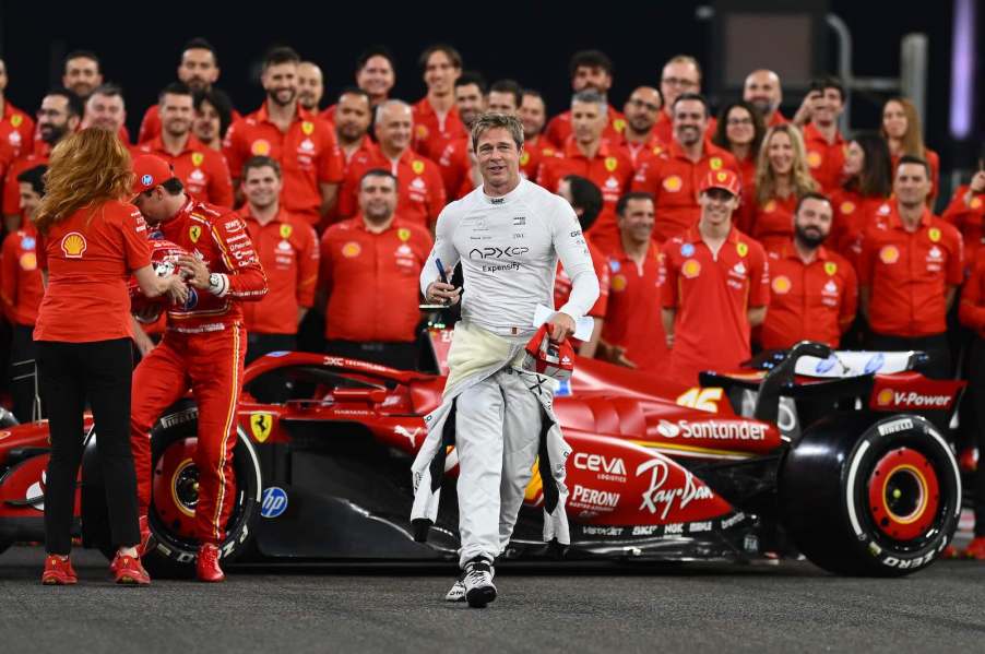Actor Brad Pitt stands with team Ferrari and a Formula 1 car for a photo
