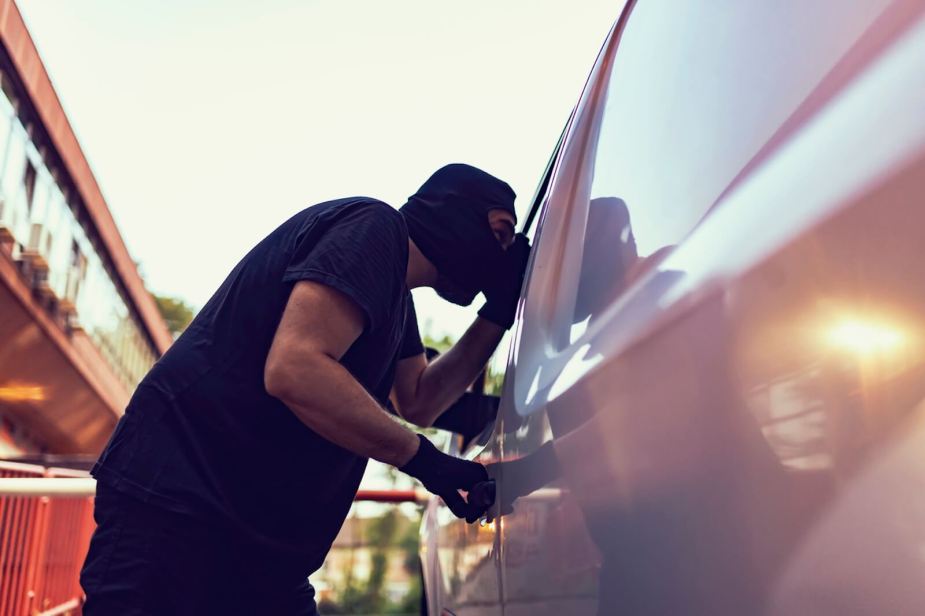 A car thief cases a large vehicle, like a GMC Sierra, before stealing it.
