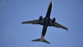 View of the underside of a passenger jumbo jet with Delta painted on it, from the ground.