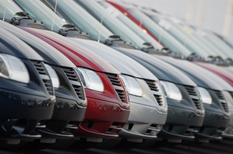 Row of Dodge Caravan minivans waiting at a dealership.
