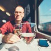 Train traveler sits at a table with two glasses of wine.
