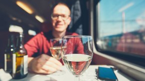 Train traveler sits at a table with two glasses of wine.