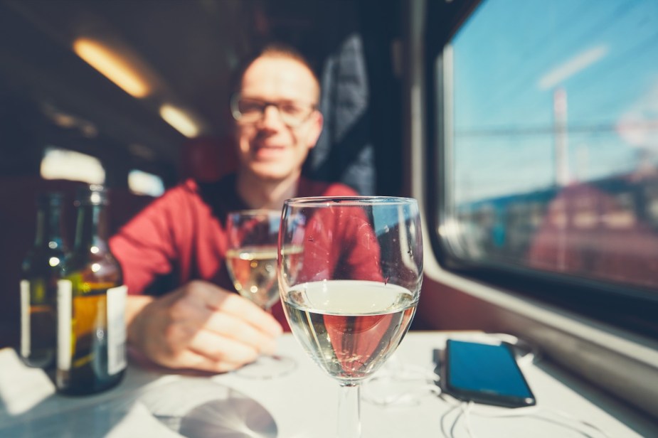 Train traveler sits at a table with two glasses of wine.