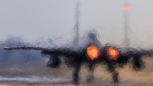 F-15D fighter taxis onto the runway, its jet engines glowing.
