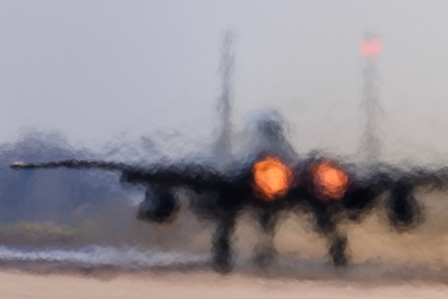 F-15D fighter taxis onto the runway, its jet engines glowing.