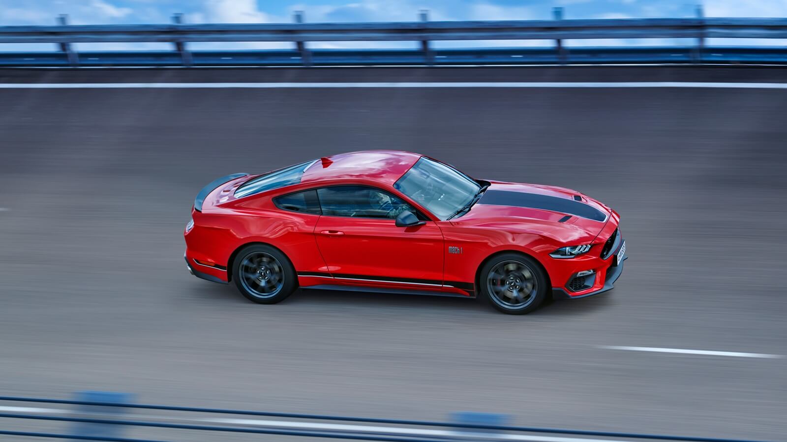 A Ford Mustang Mach-1 drives around a banked corner on a track.