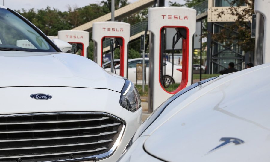 Ford car and Tesla EV at a Supercharger station.